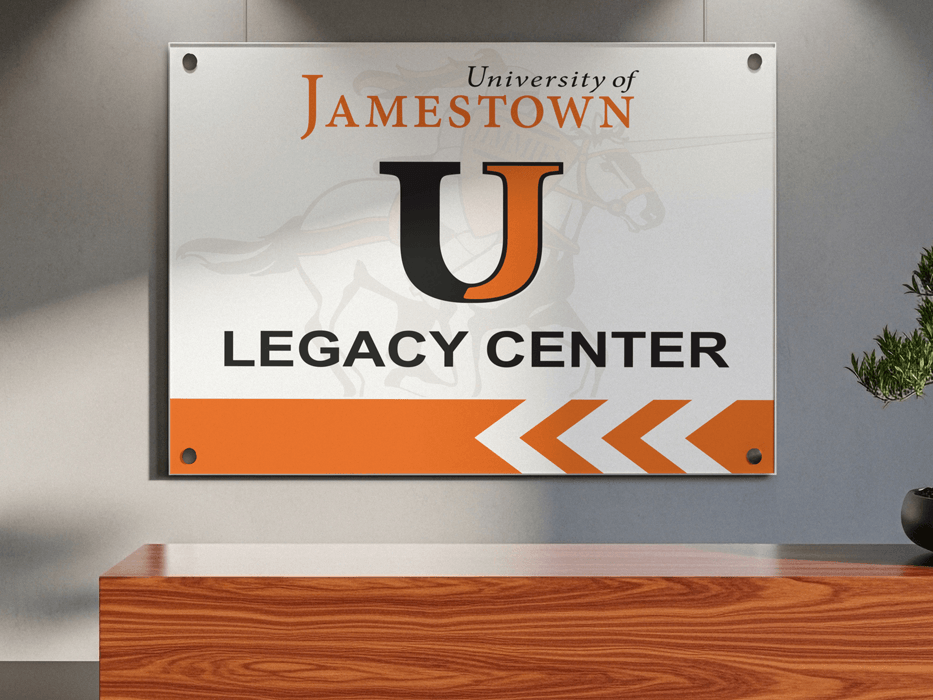 University of Jamestown Legacy Center sign on a wall above a wooden desk on campus in Jamestown, ND.